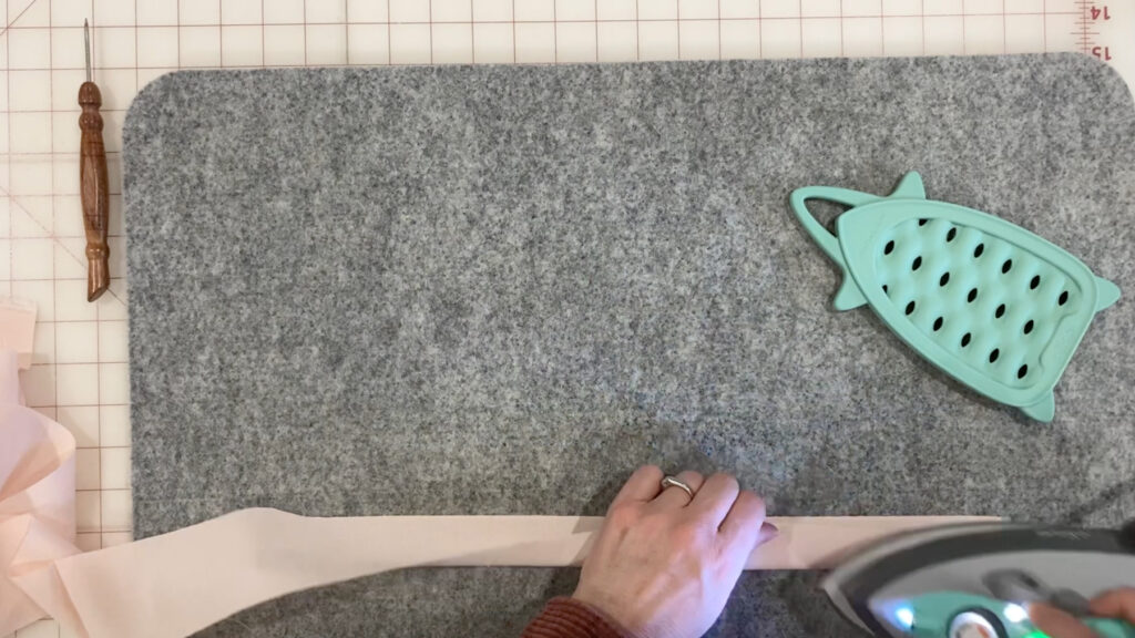 Pressing the long binding strip in half lengthwise with an iron, wrong sides together.