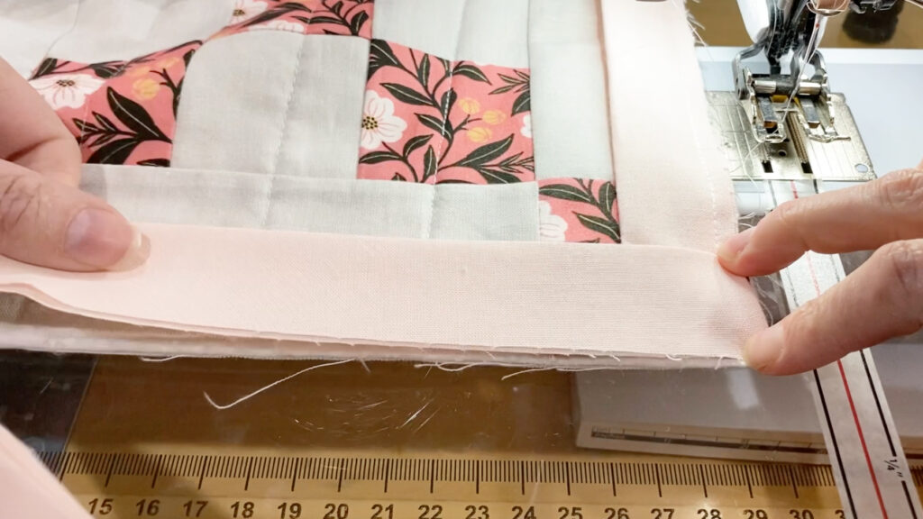 Folding the binding back down over itself to create a mitered corner.