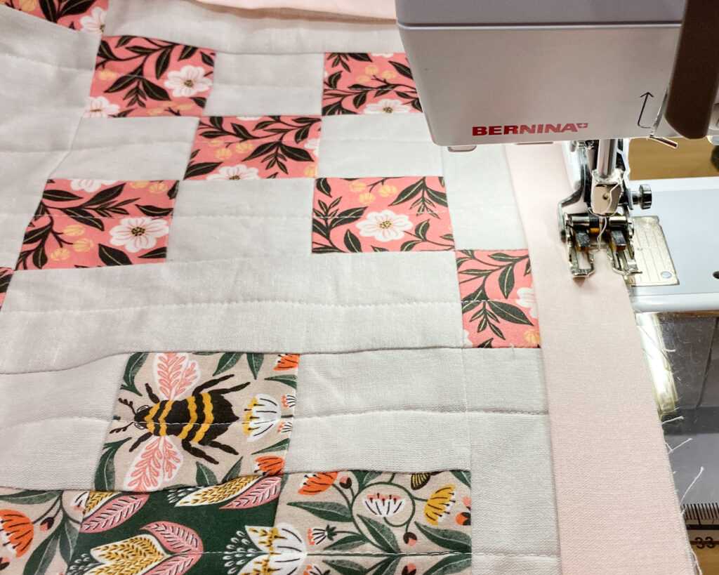 Starting to sew the binding to the quilt at a sewing machine, leaving a 12" tail.