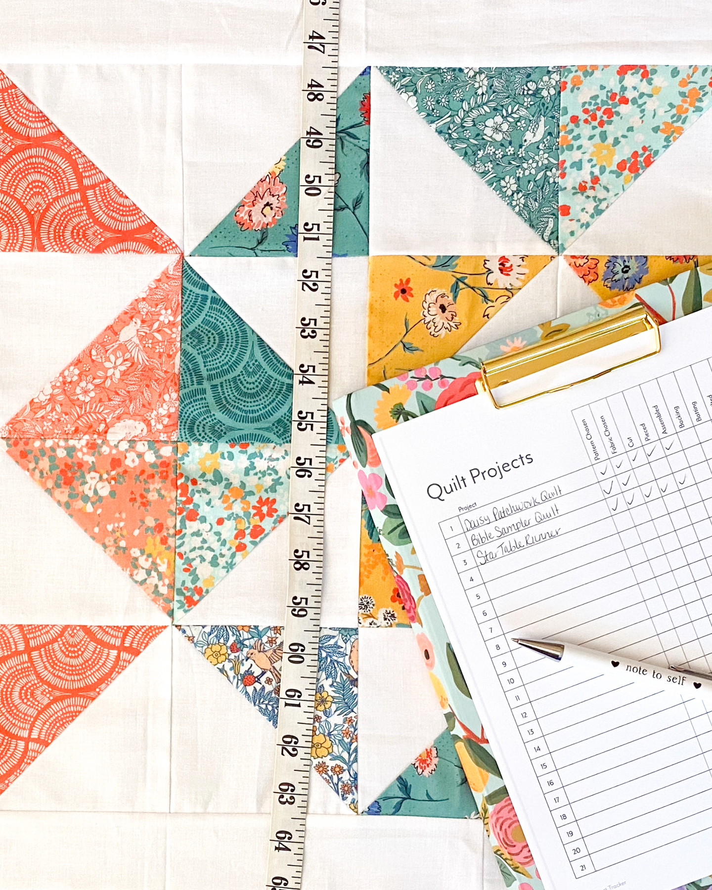Free Quilt Project Tracker printed and displayed on a finished quilt at a cutting table