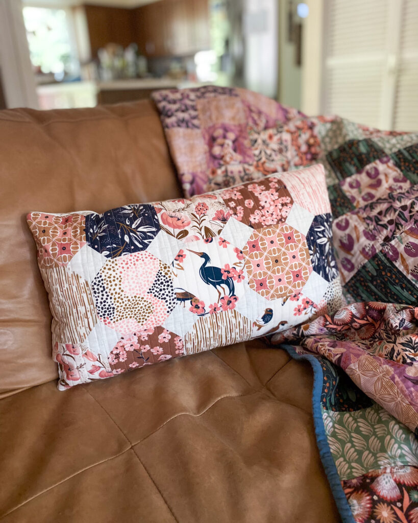 Honeycomb lumbar pillow styled on a chair, handmade with modern floral prints from the Enchanted fabric line