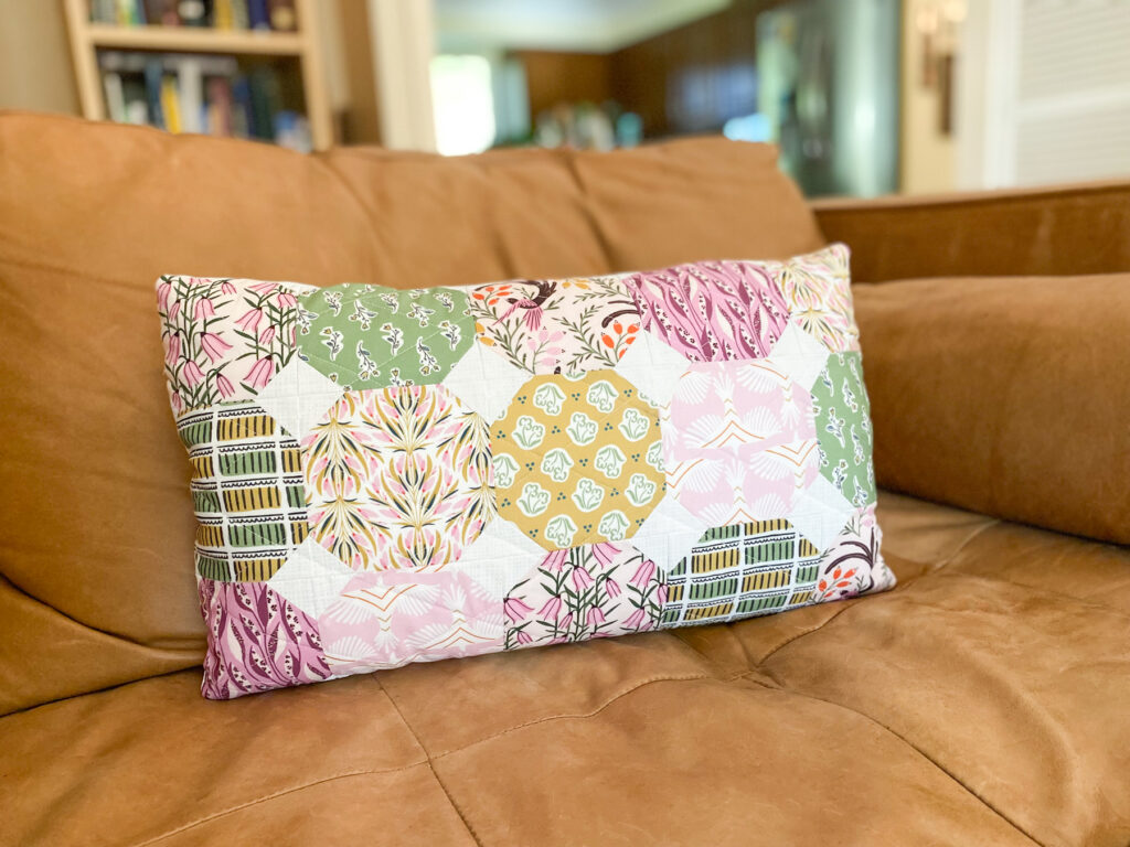 Finished quilted lumbar pillow with diamond straight line quilting displayed on brown leather couch